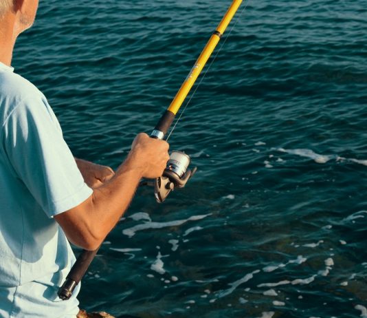 Histórias de quem ainda não ganhou 1 milhão. Homem em alto mar com a vara de pesca na mão.